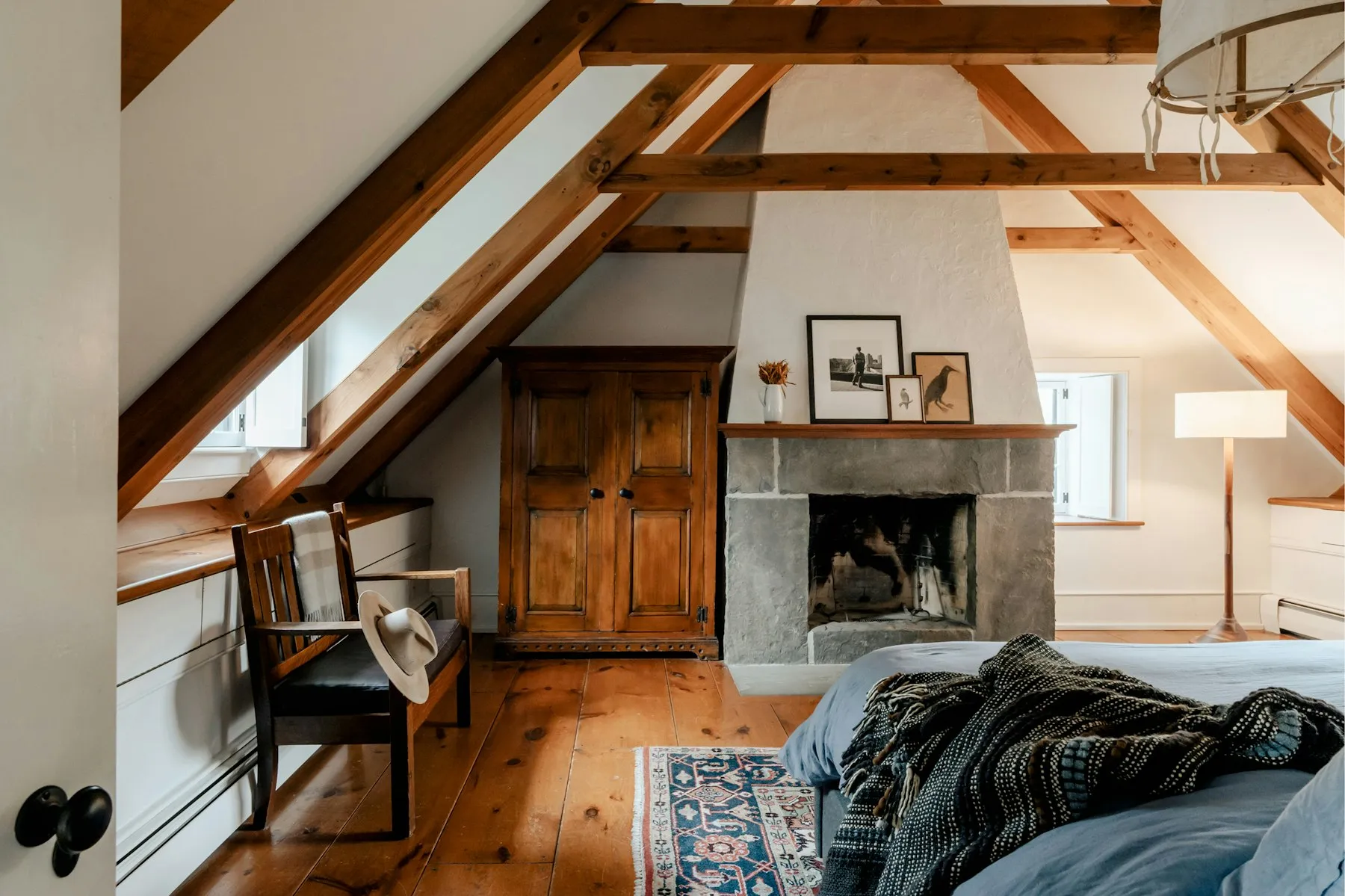 Chambre aménagée sous les combles, poutres apparentes et cheminée